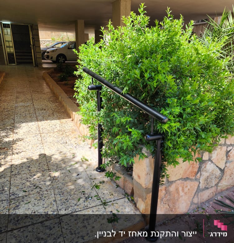 מעקה מתכת שחור ליד שיח ירוק